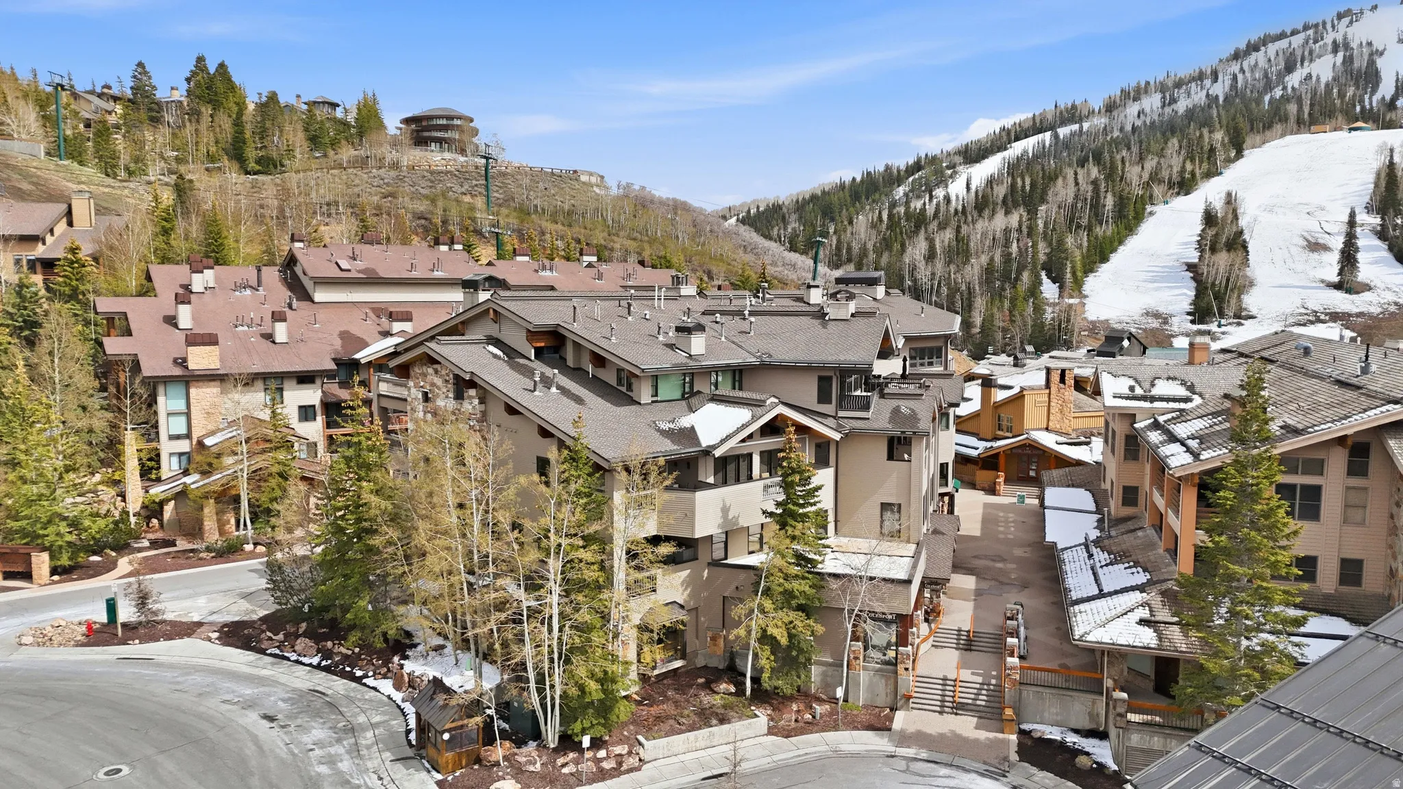 Hillside multi-story buildings featuring stone and stucco exteriors, multiple balconies, and a paved street