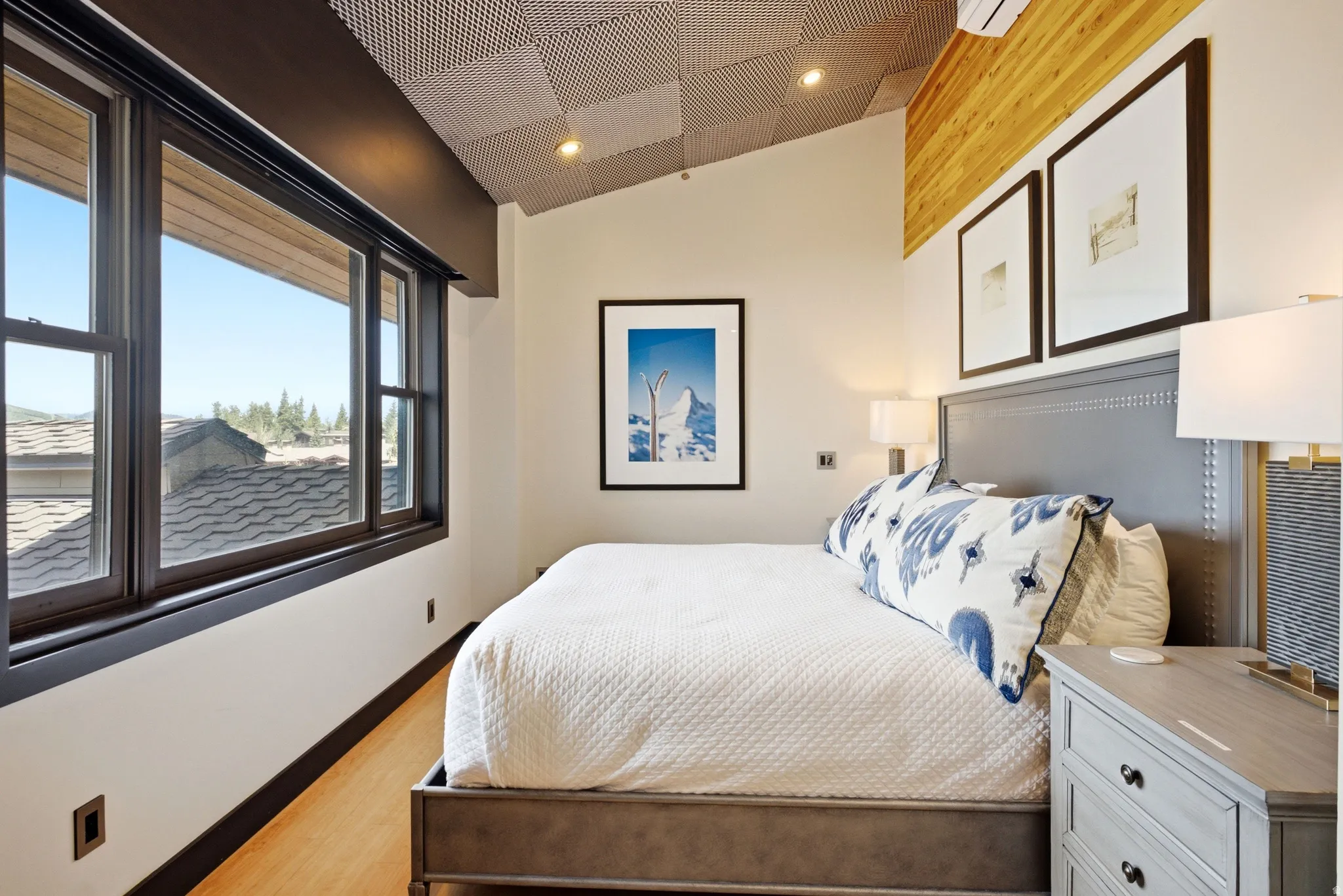 Room featuring a sloped ceiling with recessed lighting, wood-finish flooring, and a large window with dark trim