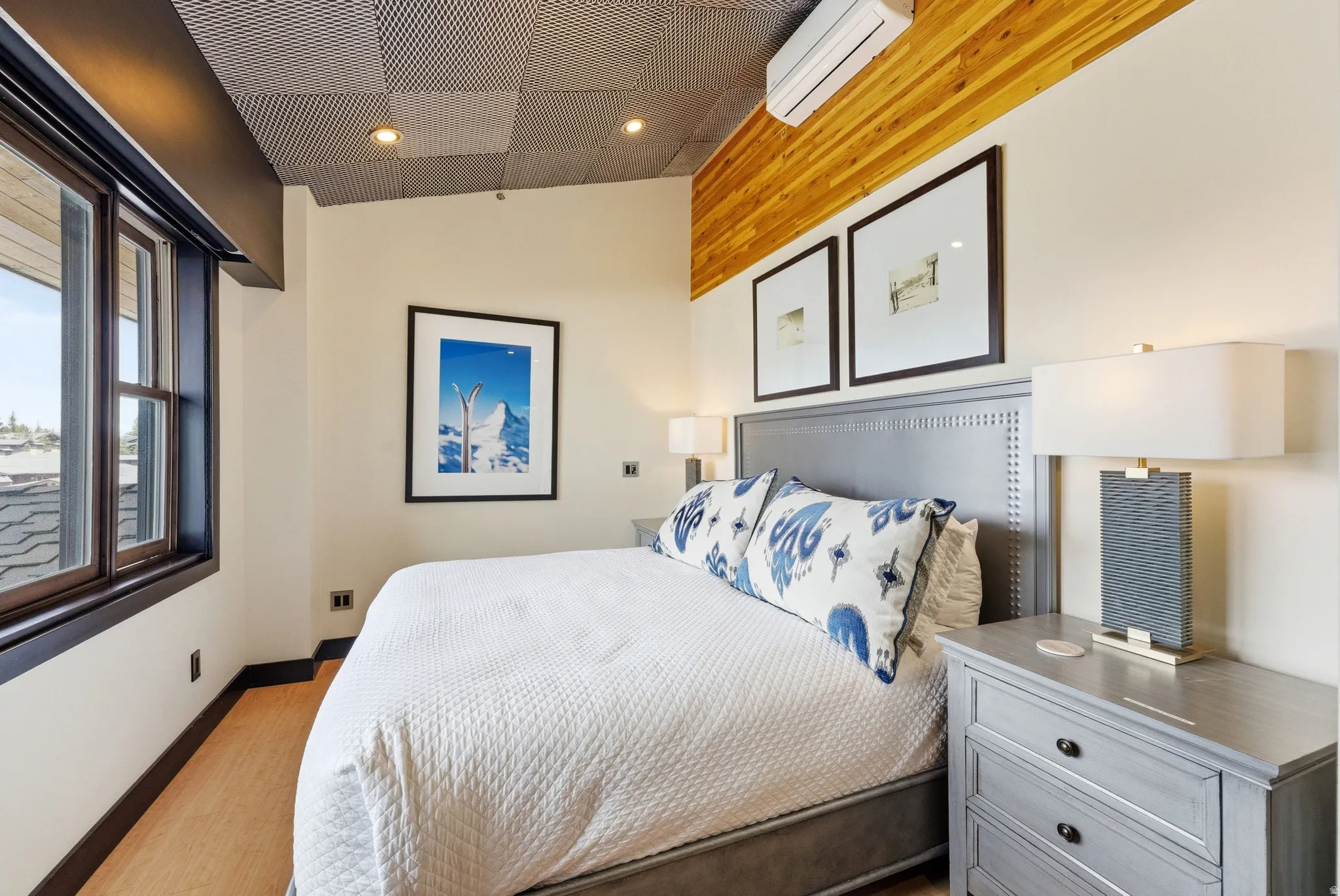 Bedroom with wood-finish flooring, a textured acoustic ceiling, and a wood accent wall