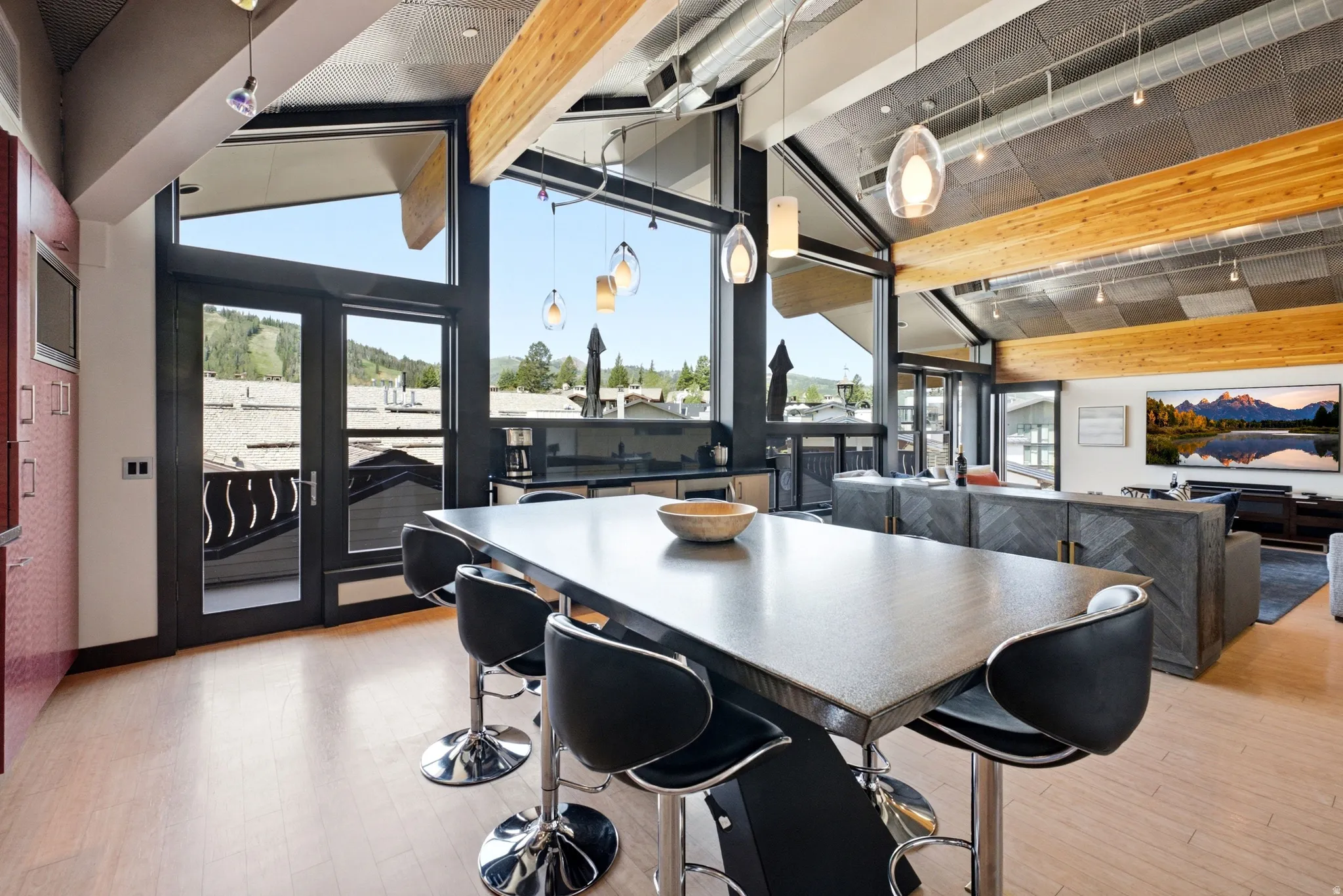 Spacious interior featuring a large island with seating, wood-finish flooring, and exposed wood ceiling beams