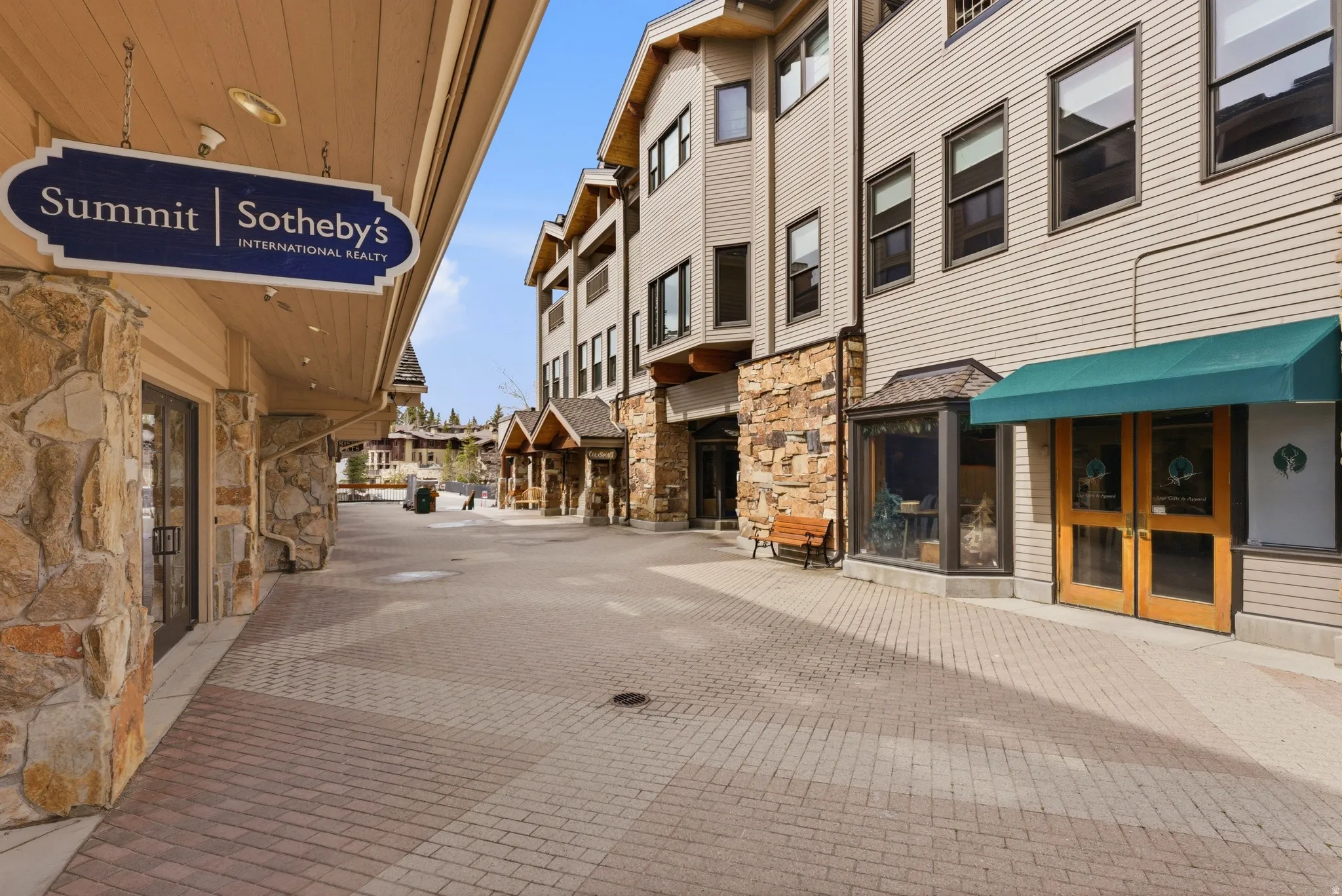 Commercial streetscape featuring a paved walkway, stone facade details, and multiple storefronts