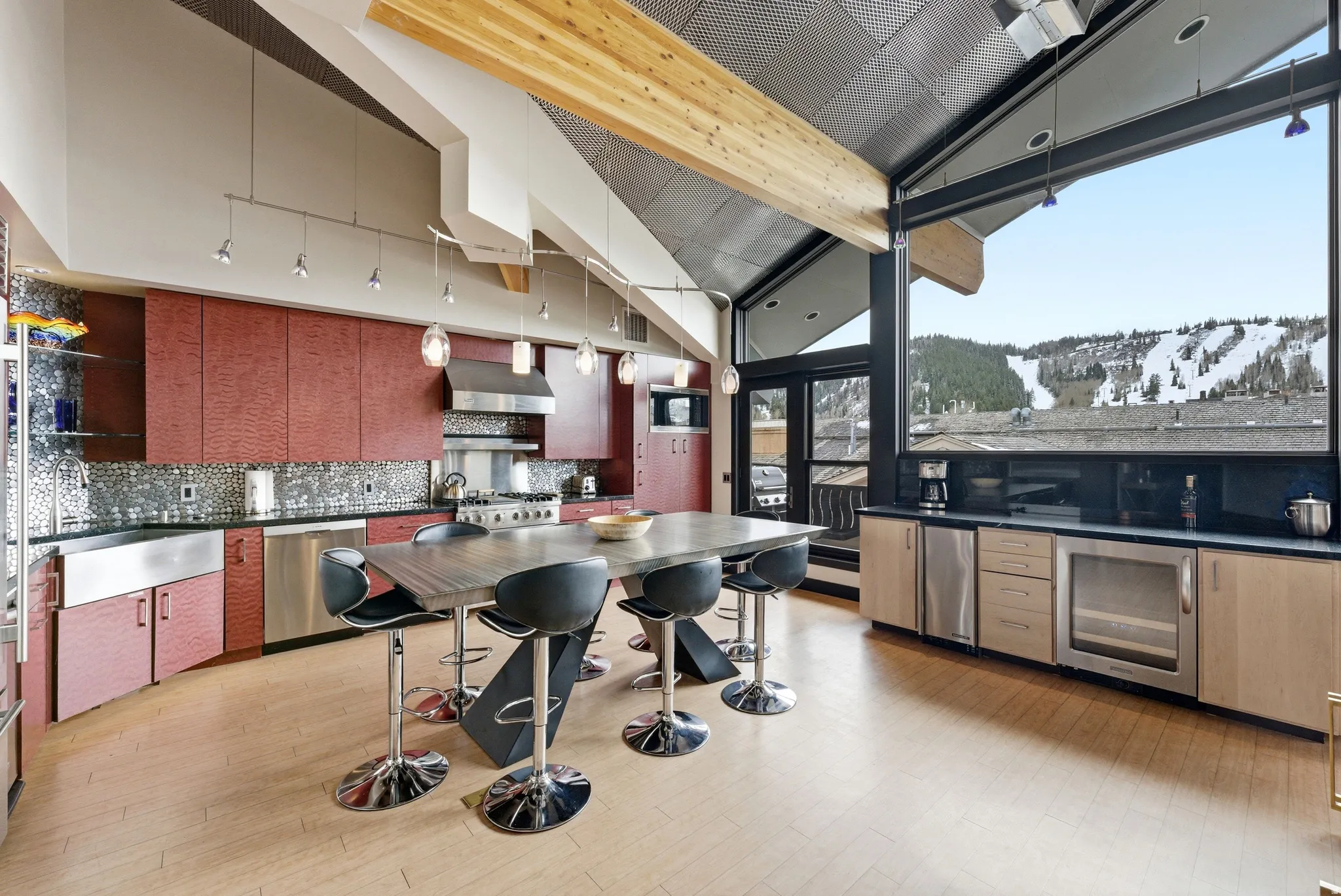 Open-concept kitchen featuring an expansive window with mountain scenery, red cabinetry, stainless steel appliances, and a central island with seating