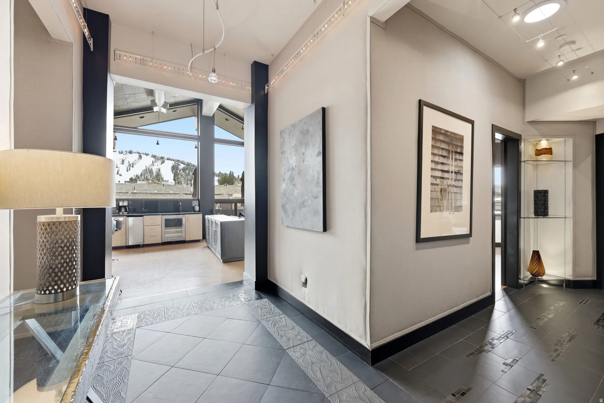 Expansive window wall showcasing mountain scenery, complemented by durable tile flooring with decorative inlay