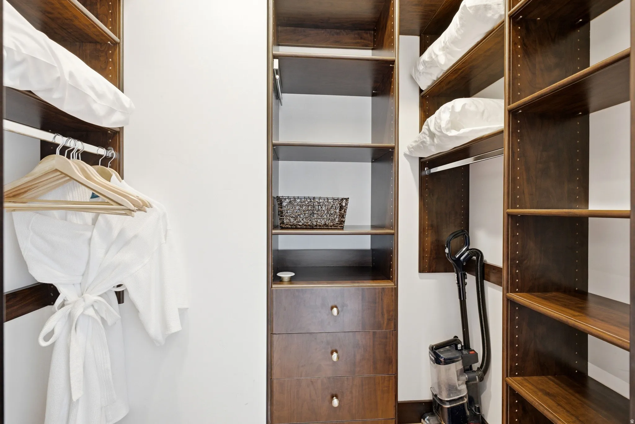 Custom closet system featuring dark wood-finish shelving and integrated drawer storage
