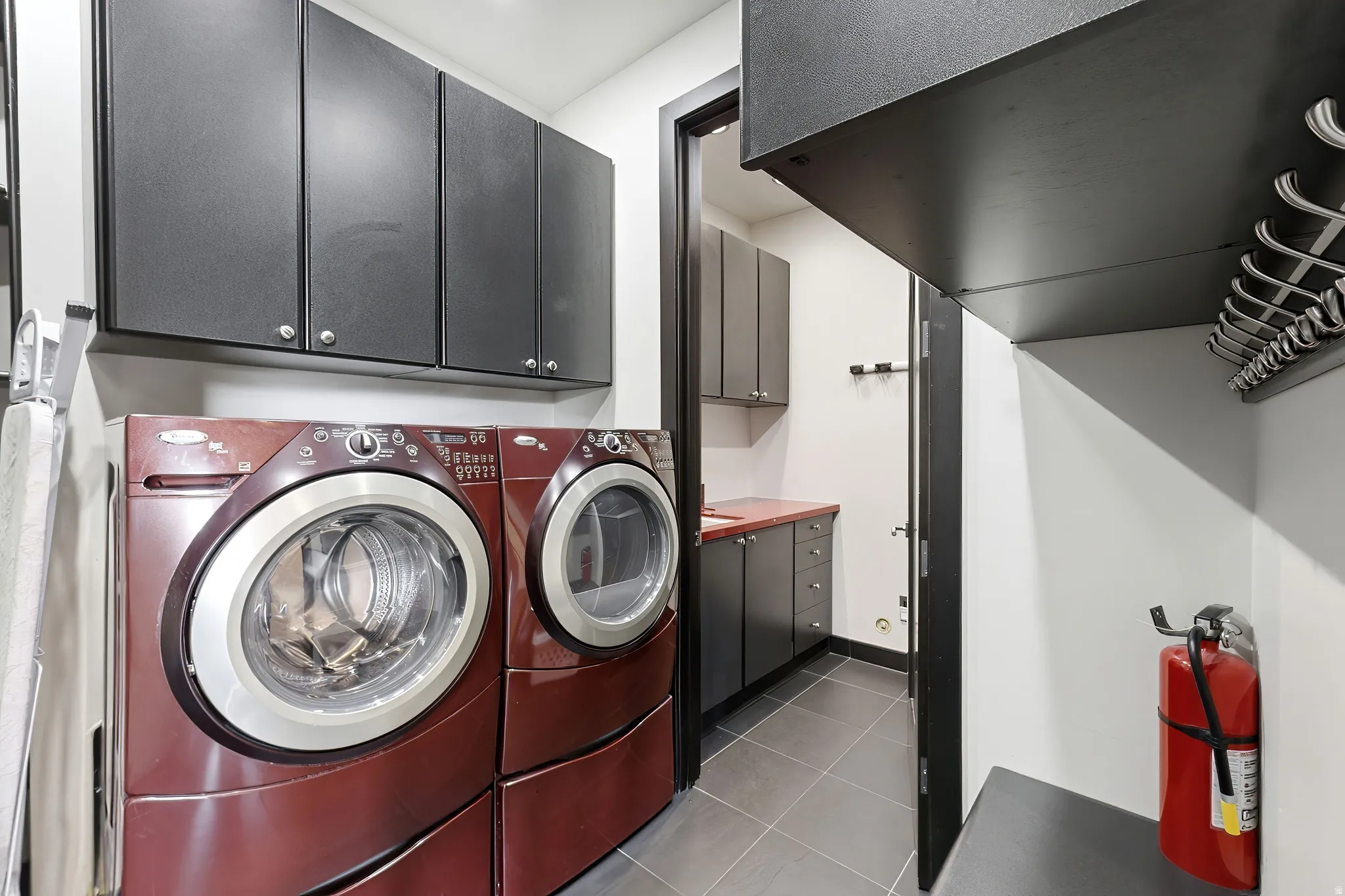 Functional laundry area featuring a washer and dryer, dark cabinetry, and tile flooring