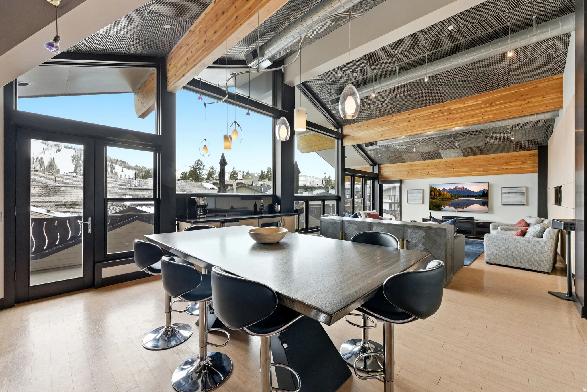 Spacious open-concept living area featuring a vaulted ceiling with exposed wood beams and perforated ceiling panels