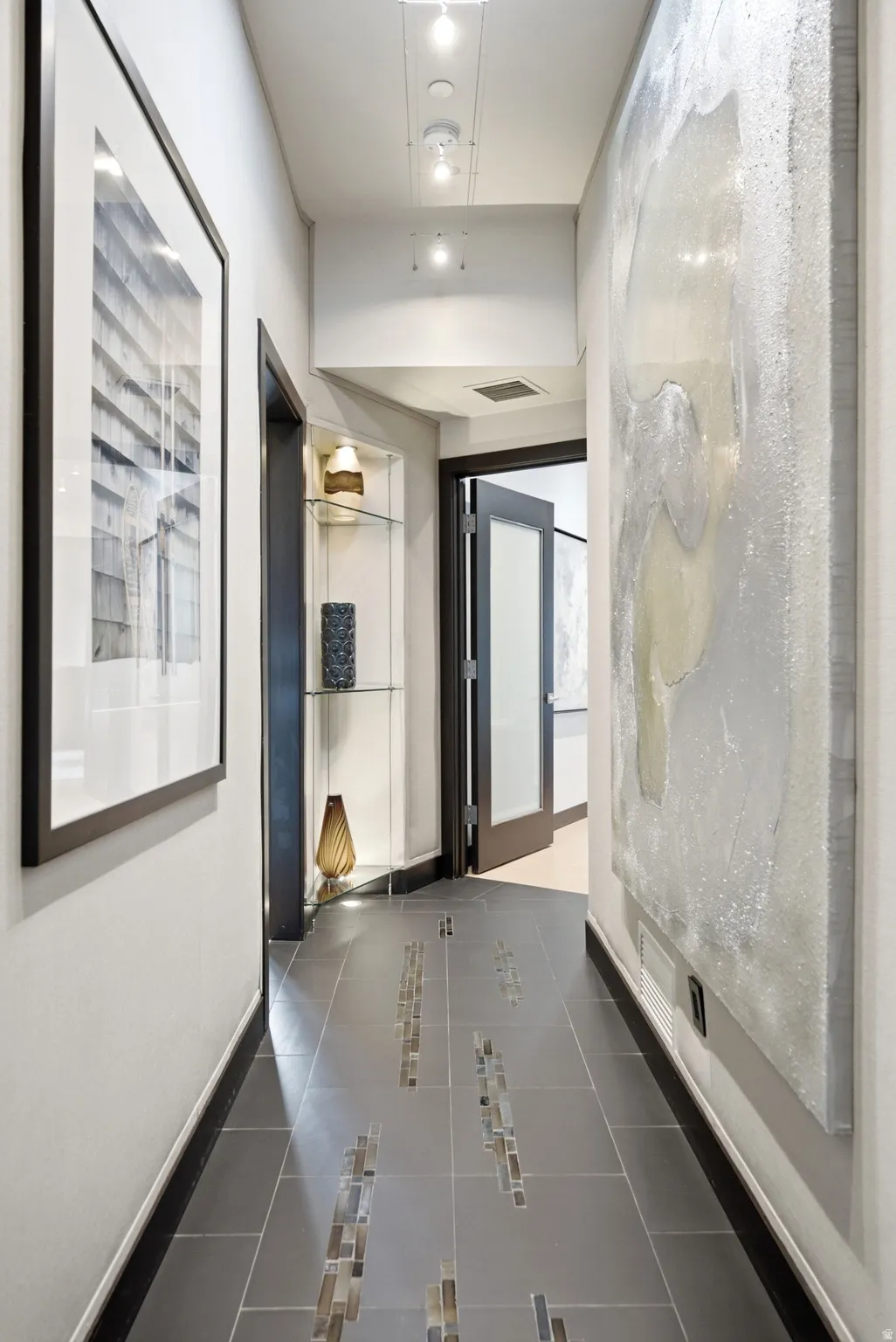 Hallway featuring dark tile flooring with mosaic tile inlay, recessed lighting, and a built-in display niche with glass shelving