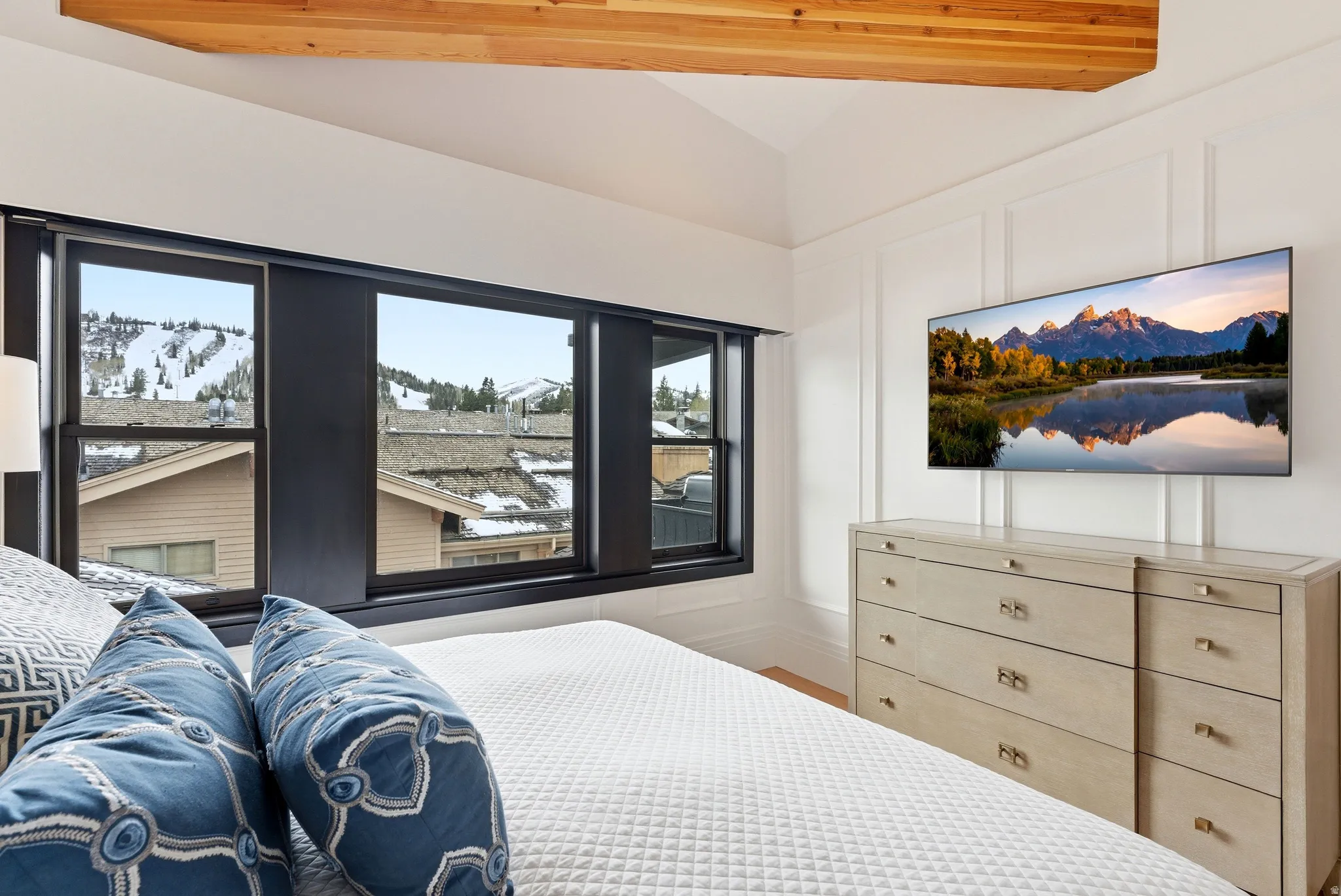 Expansive windows showcasing mountain scenery, complemented by a vaulted ceiling with exposed wood beams