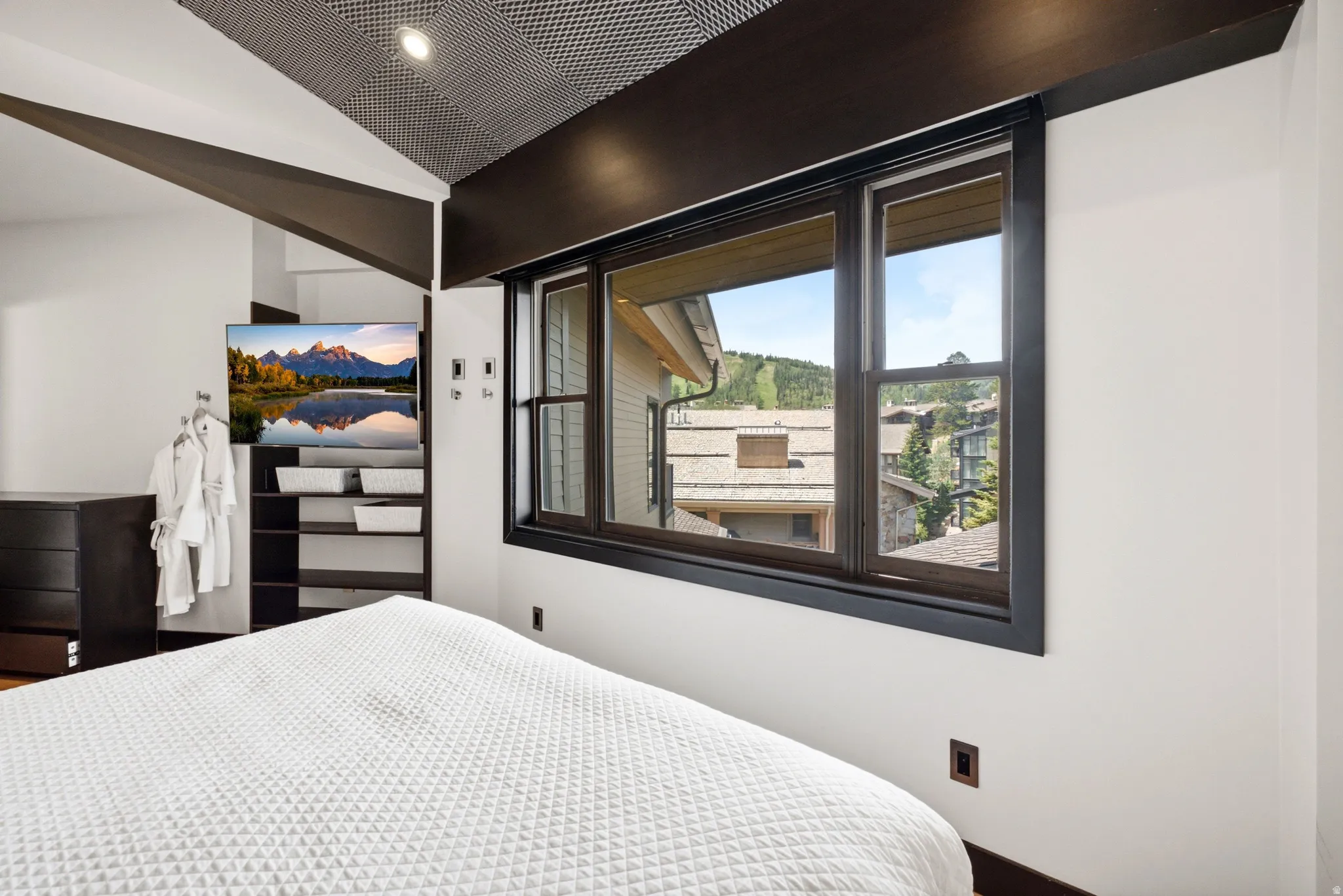 Contemporary ceiling design with integrated lighting, dark wood trim, white walls, and a large window