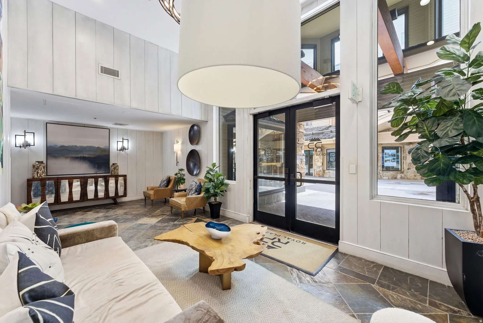 Spacious communal area featuring high ceilings, slate tile flooring, and large windows