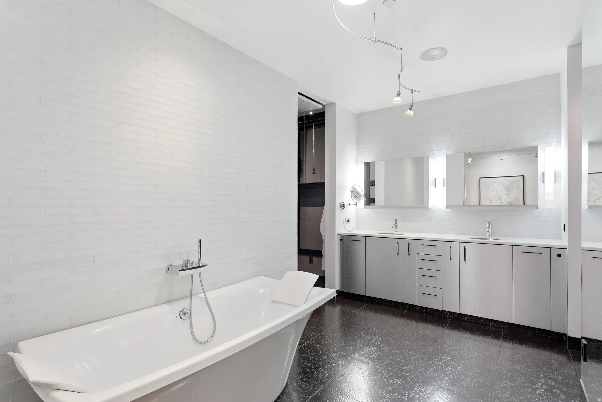 Freestanding soaking tub with chrome fixtures, set against a white tiled wall