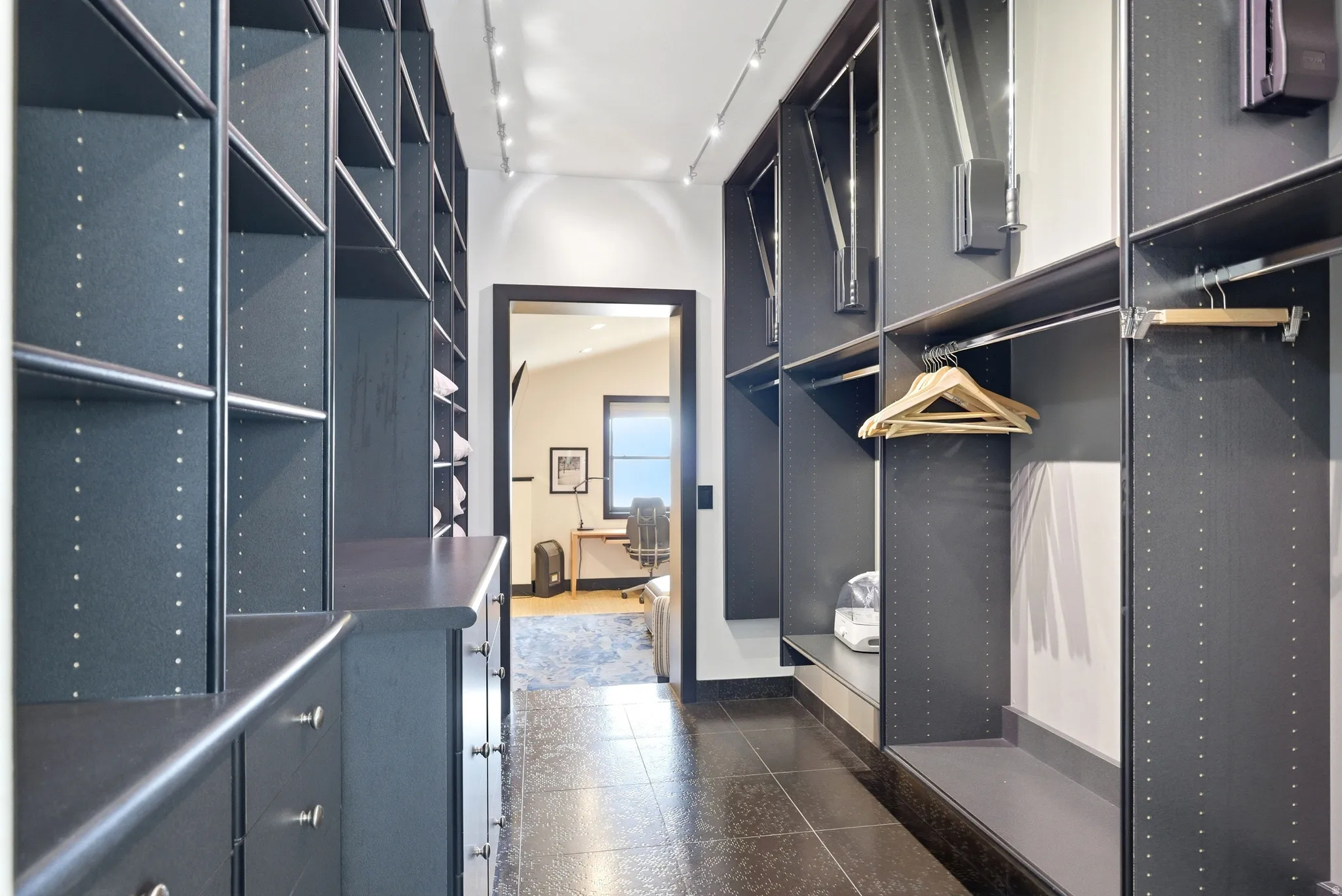 Custom dark cabinetry with built-in shelving, hanging rods, and integrated drawers