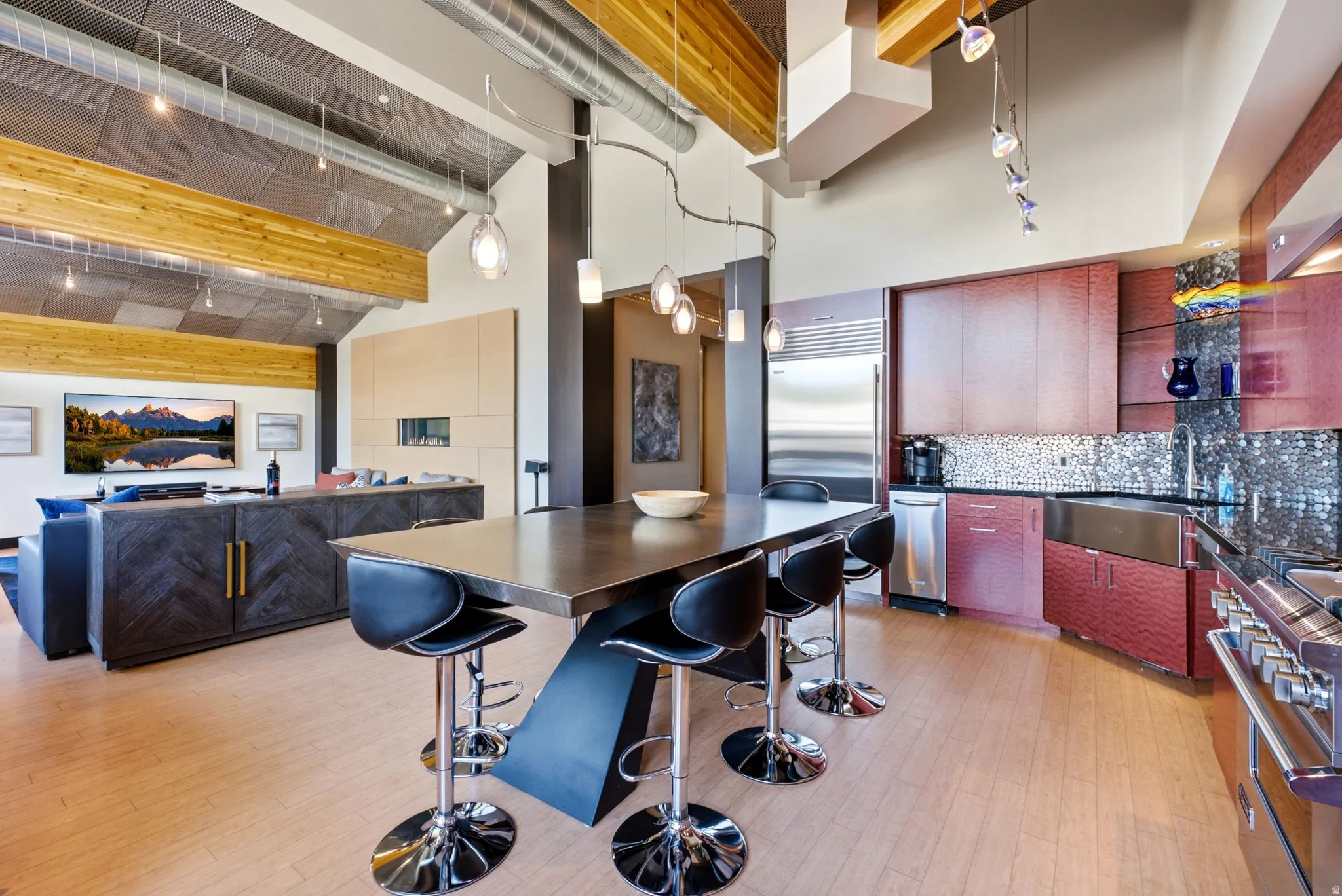 Open-concept living space featuring wood-finish flooring, exposed wooden beams, and a vaulted ceiling