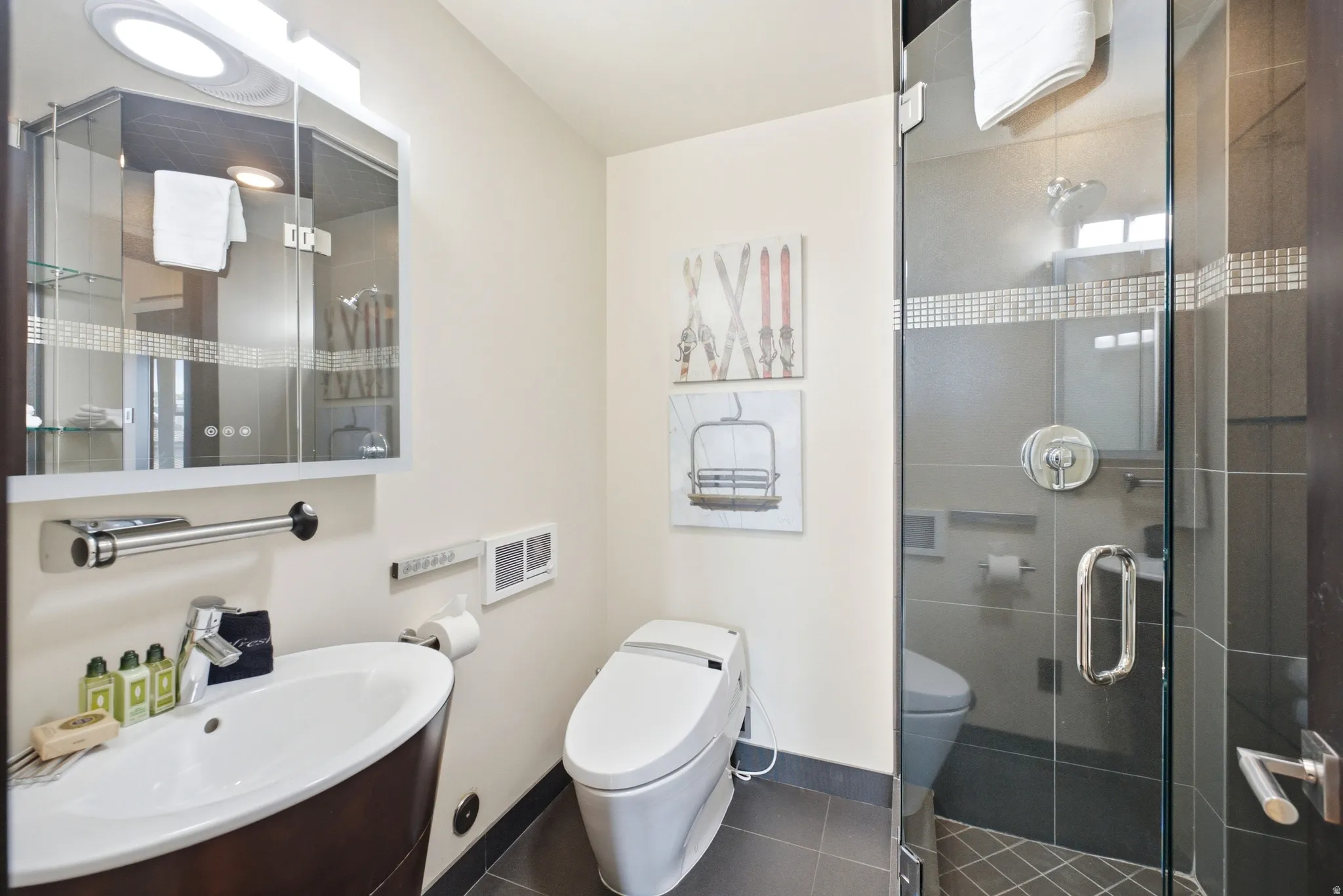 Bathroom featuring a contemporary vanity with an oval basin, a wall-mounted mirrored cabinet, a modern toilet, and a glass-enclosed shower with tile surround