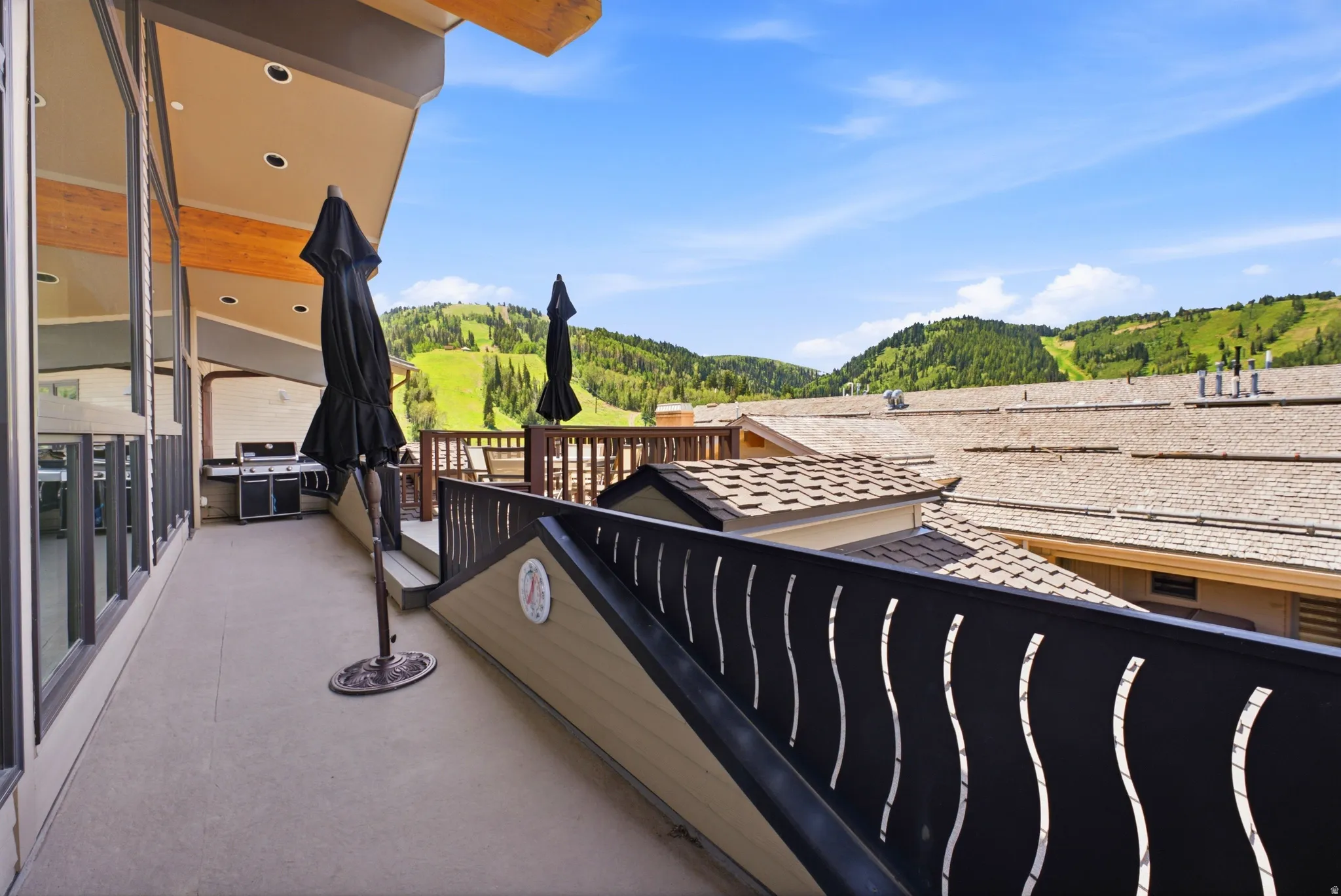 Spacious outdoor patio with a built-in grill, recessed lighting, and a decorative metal railing