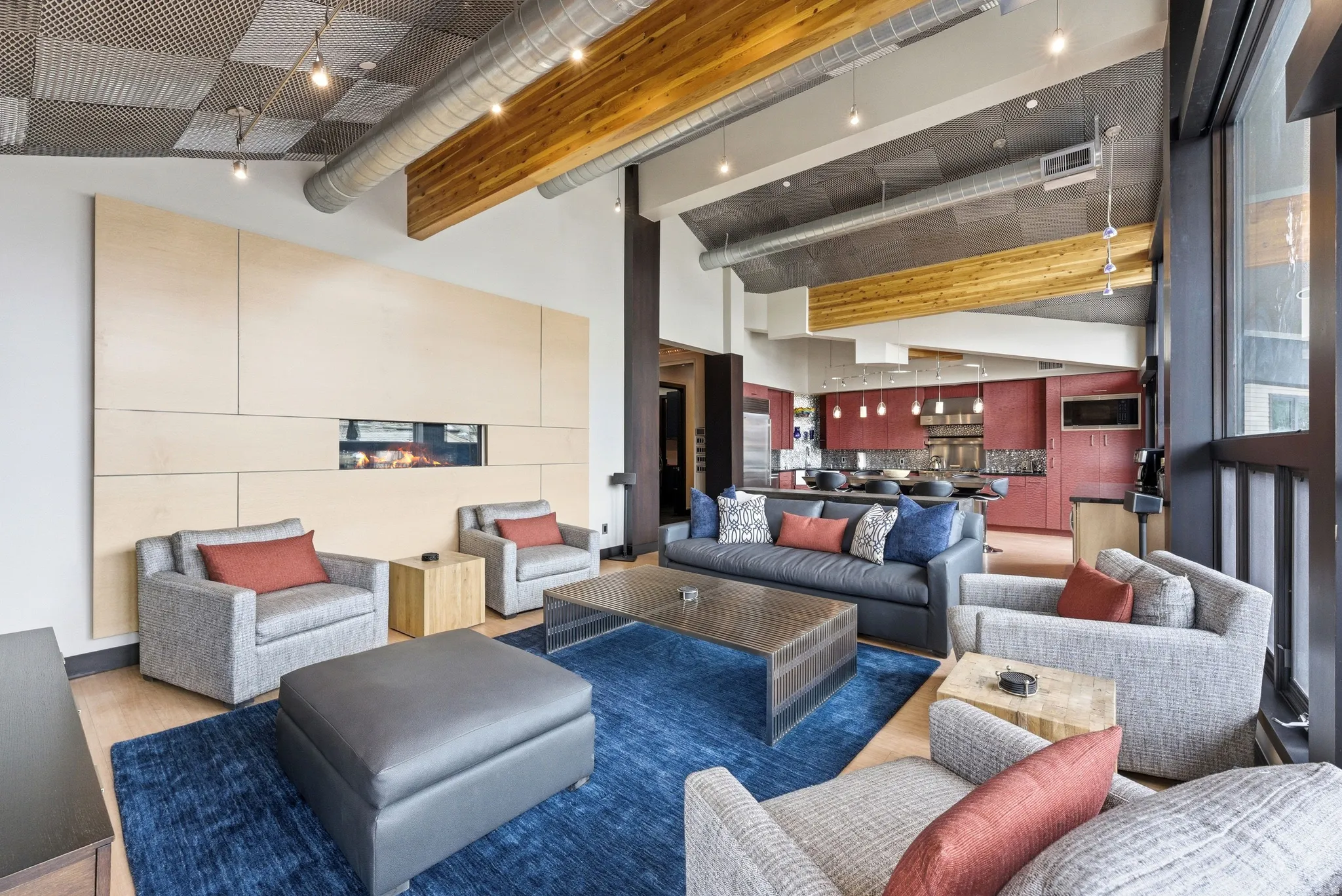 Great room featuring a linear fireplace within a paneled wall, exposed wood beams, vaulted ceilings, and large windows