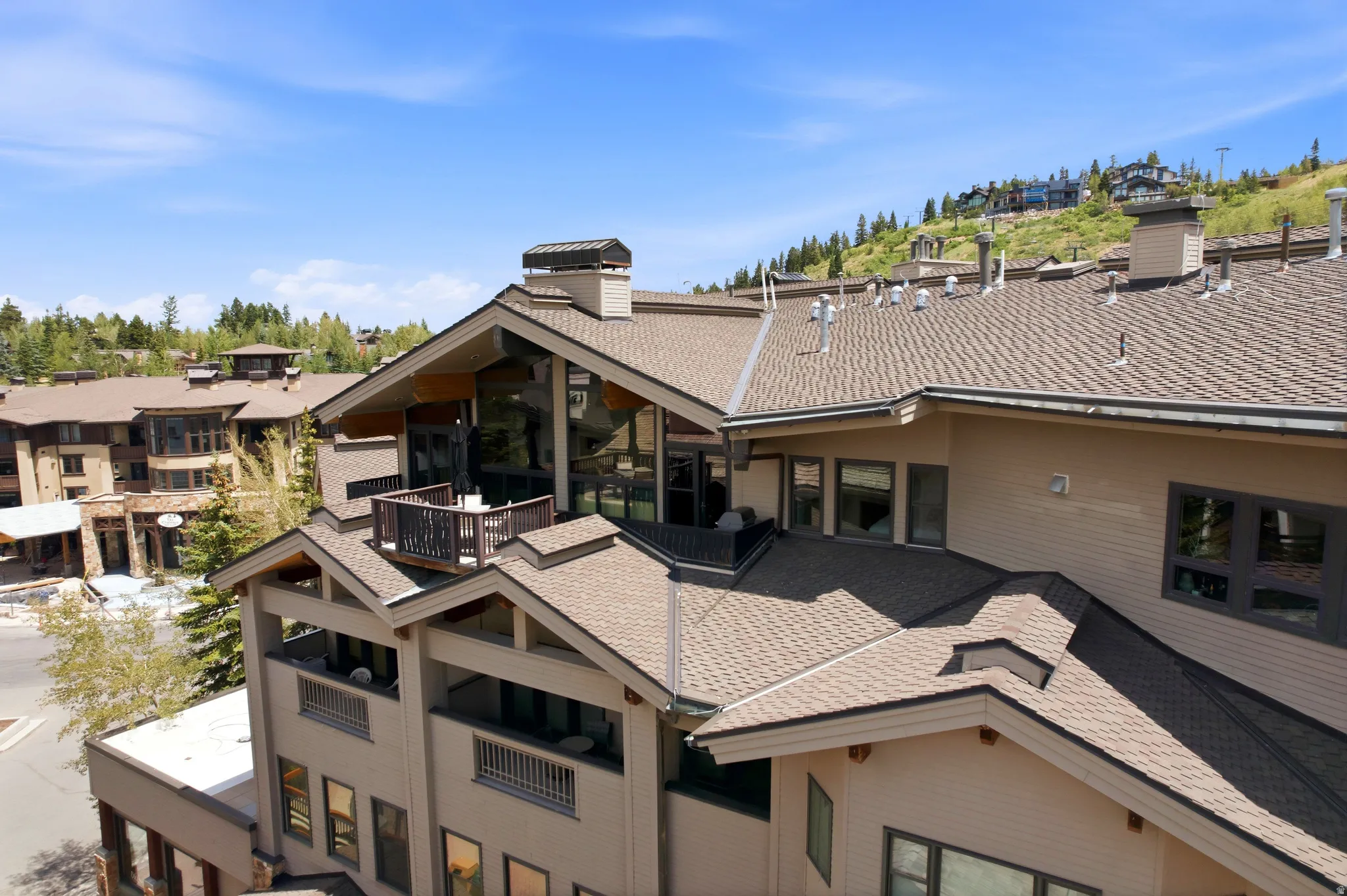 Multi-level property exterior with extensive rooflines, multiple private balconies, expansive windows, and a prominent chimney feature