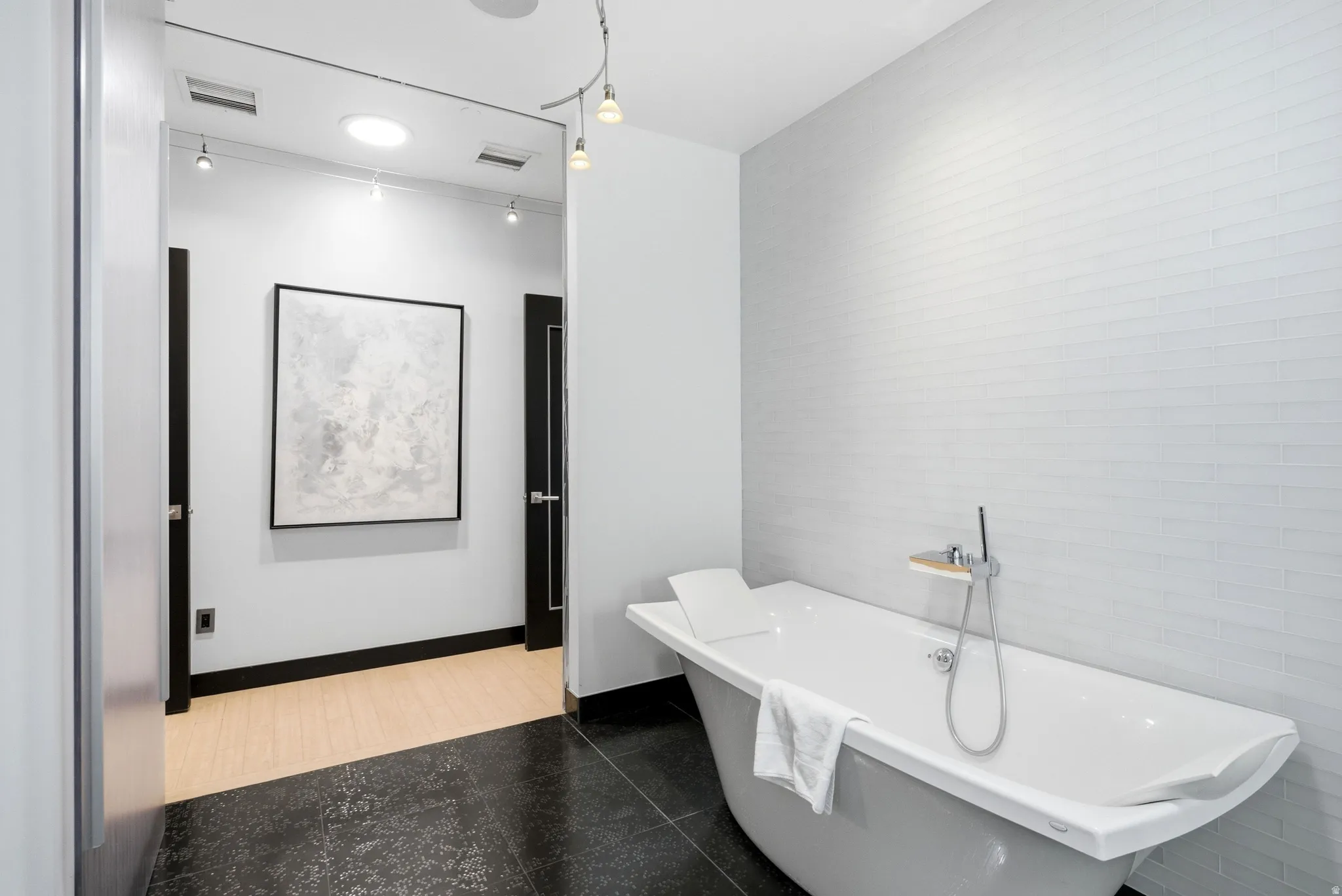 Freestanding soaking tub with chrome fixtures, set against a tiled wall