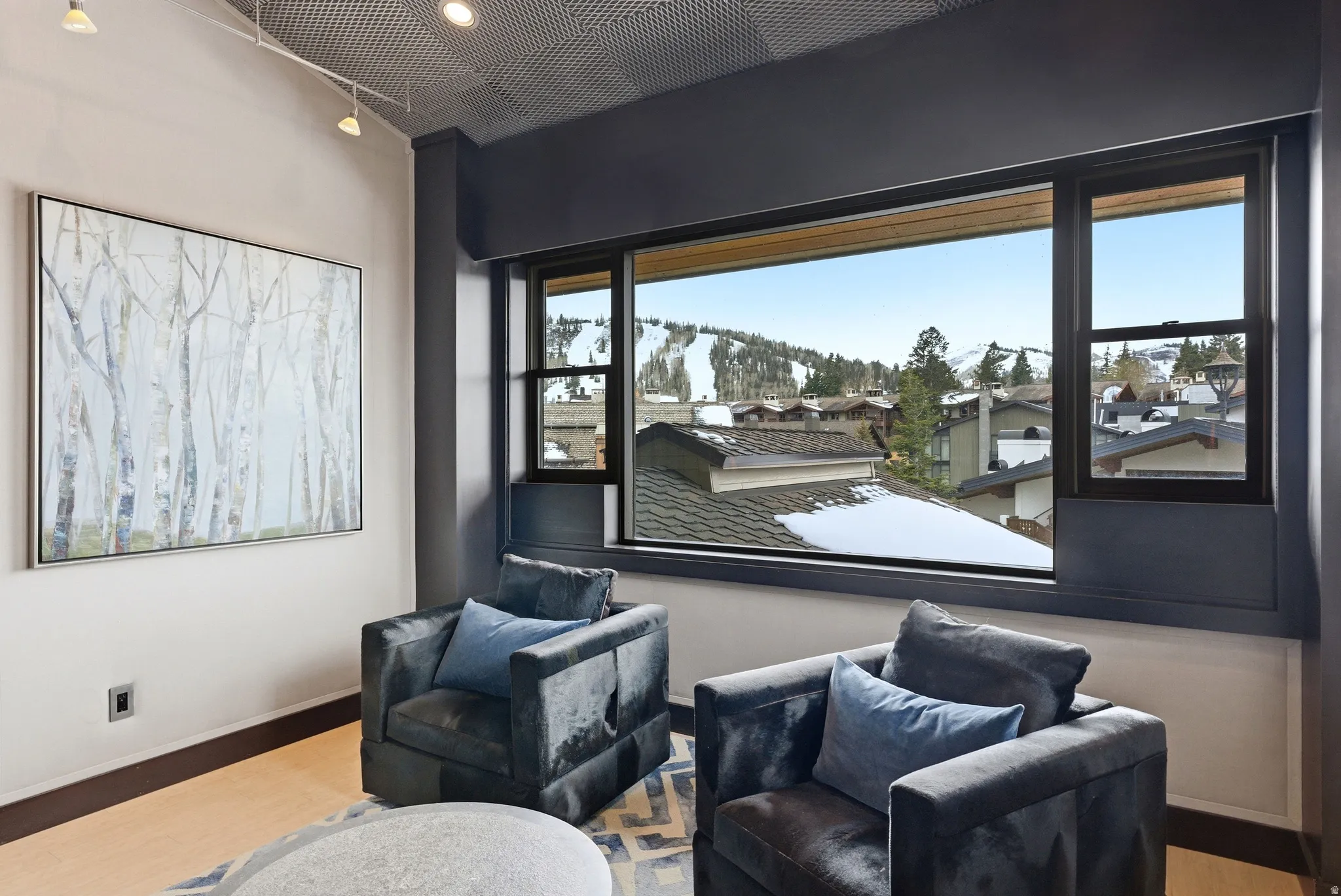 Expansive window framing snow-capped mountains and distant rooftops