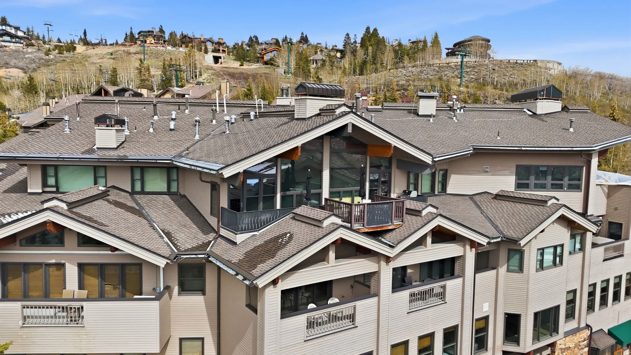 Multi-level building exterior featuring multiple private balconies with dark railings, a prominent gable roof, and extensive windowing