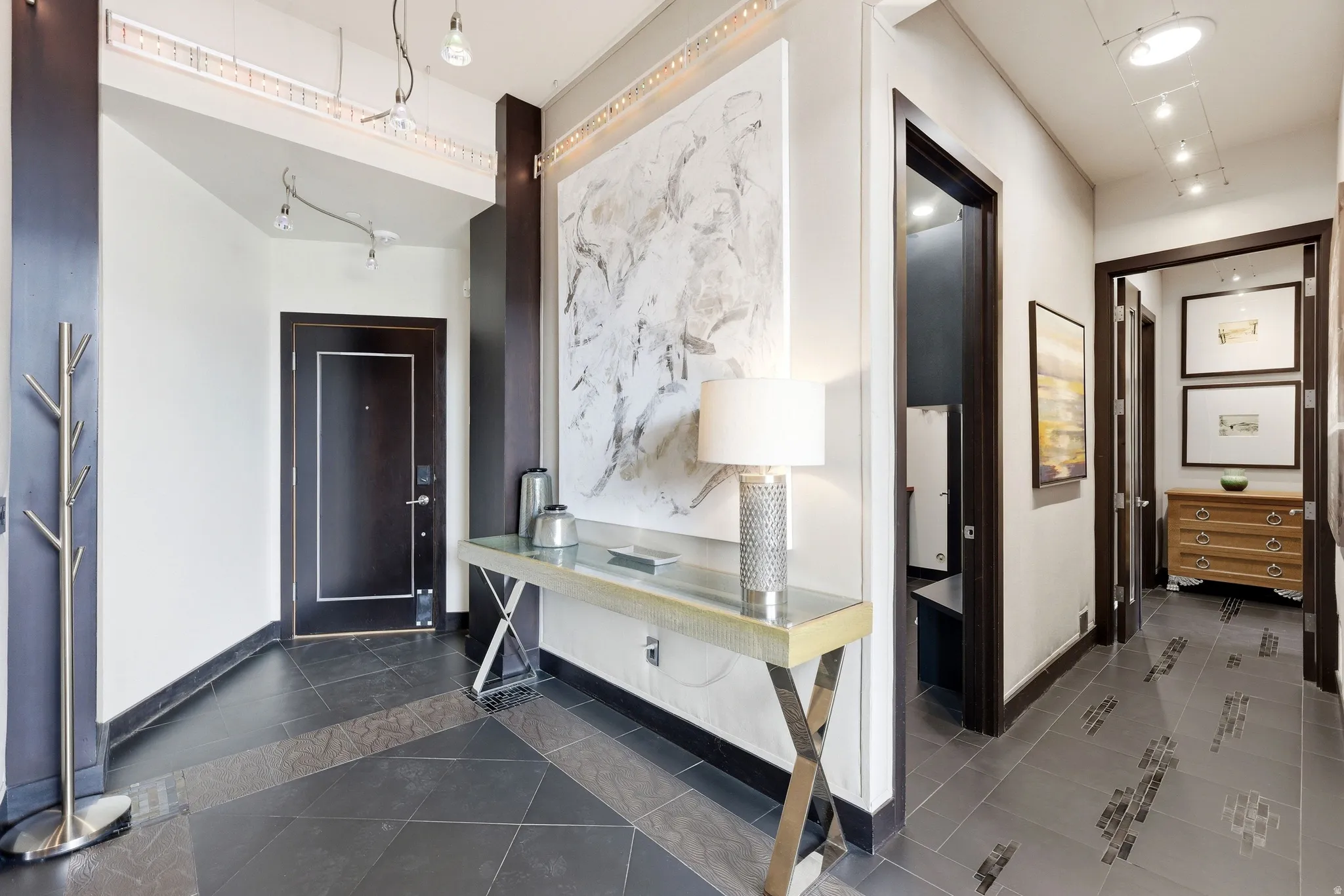 Entryway featuring black tile flooring with geometric inlays, dark trim, and white walls