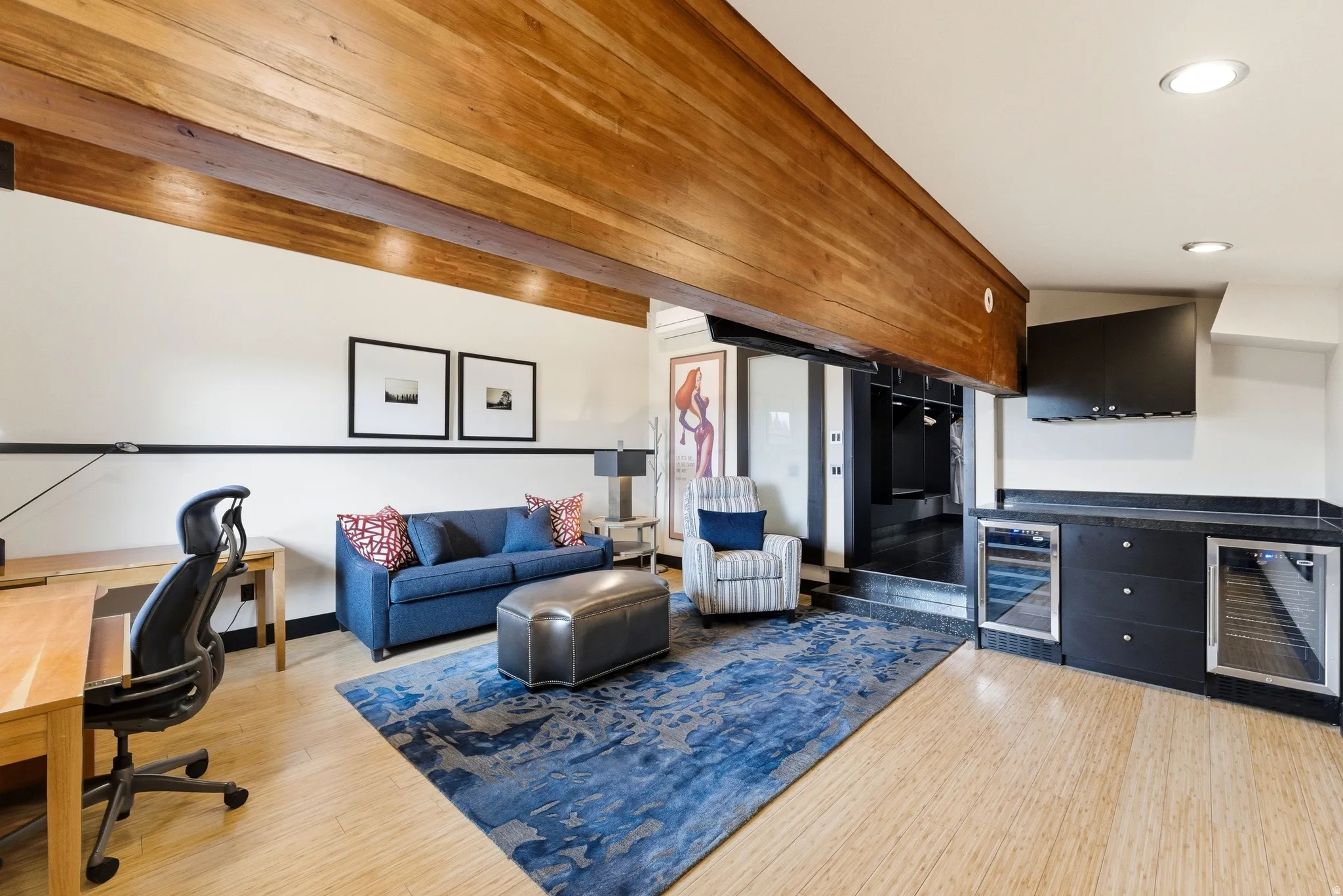 Open-concept living area with wood-finish flooring, exposed ceiling beams, and recessed lighting