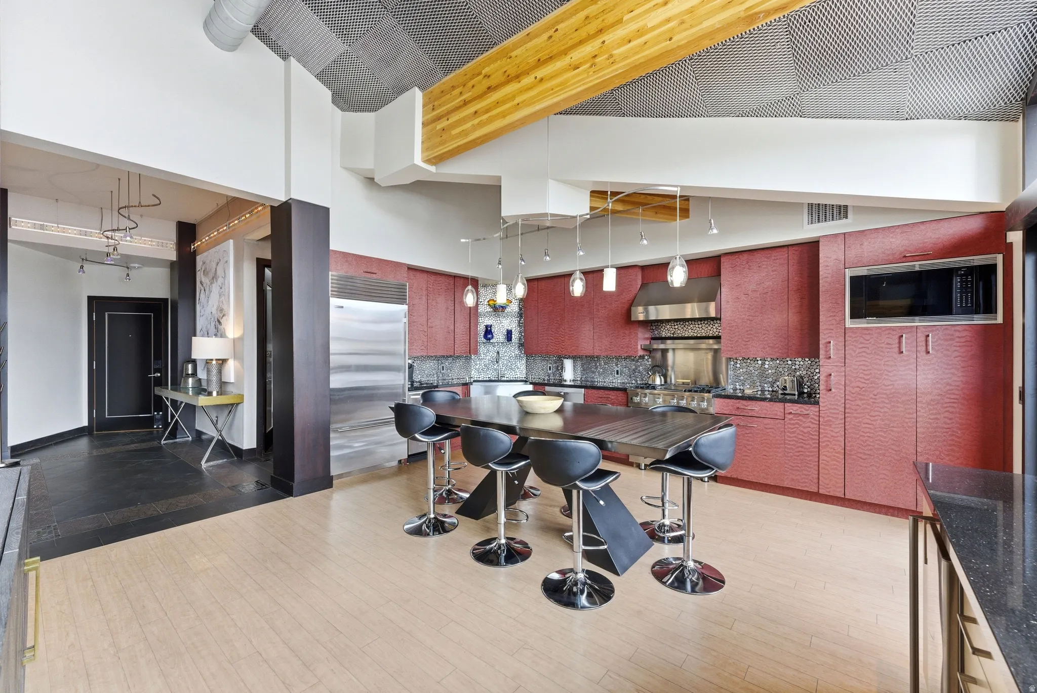 Contemporary kitchen featuring red textured cabinetry, stainless steel appliances, and a built-in microwave