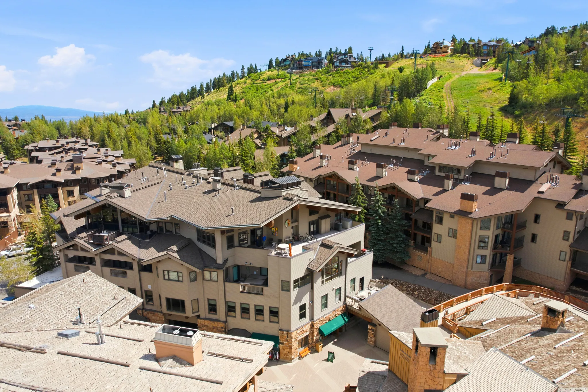 Mountainous landscape surrounding a complex of multi-story buildings featuring balconies, various rooflines, and exterior finishes of stone and siding