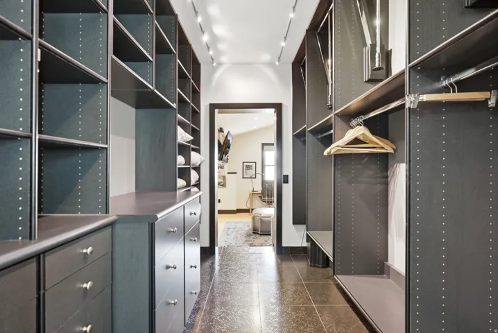 Custom closet system featuring dark wood-finish cabinetry, extensive shelving, integrated drawers with silver-tone hardware, and multiple hanging rods