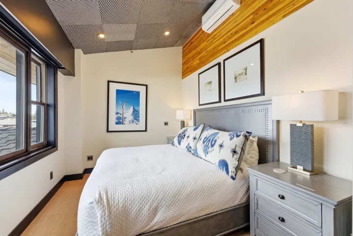 Bedroom with wood-finish flooring, a textured acoustic ceiling, and a wood accent wall