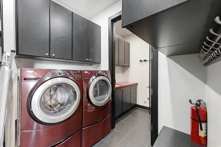 Functional laundry area featuring a washer and dryer, dark cabinetry, and tile flooring