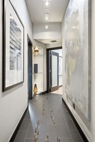 Hallway featuring dark tile flooring with mosaic tile inlay, recessed lighting, and a built-in display niche with glass shelving