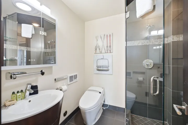 Bathroom featuring a contemporary vanity with an oval basin, a wall-mounted mirrored cabinet, a modern toilet, and a glass-enclosed shower with tile surround