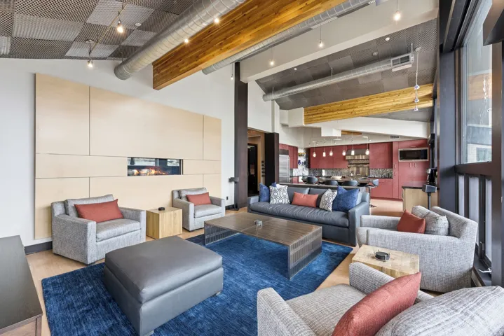 Great room featuring a linear fireplace within a paneled wall, exposed wood beams, vaulted ceilings, and large windows