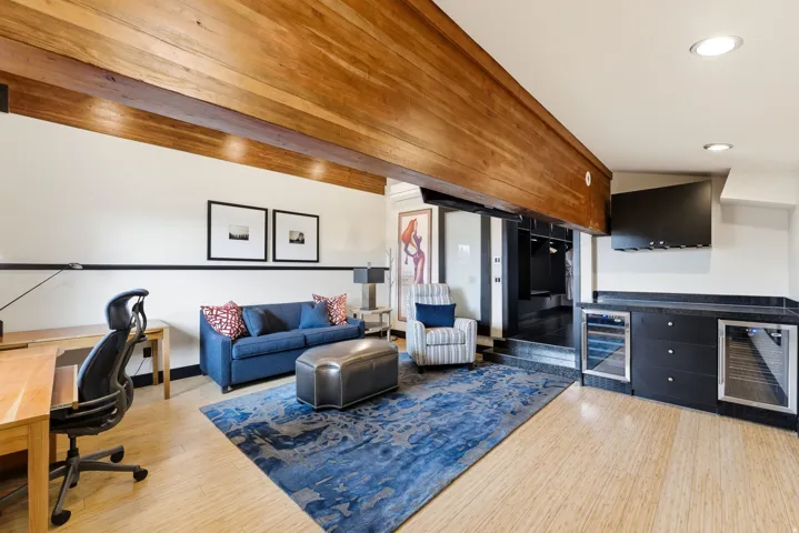 Open-concept living area with wood-finish flooring, exposed ceiling beams, and recessed lighting