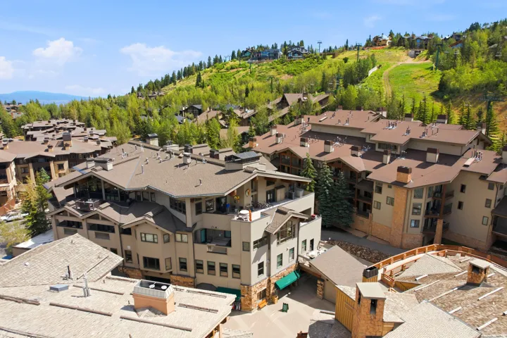 Mountainous landscape surrounding a complex of multi-story buildings featuring balconies, various rooflines, and exterior finishes of stone and siding