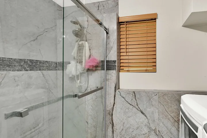 Full bath with a marble finish shower and wainscoting
