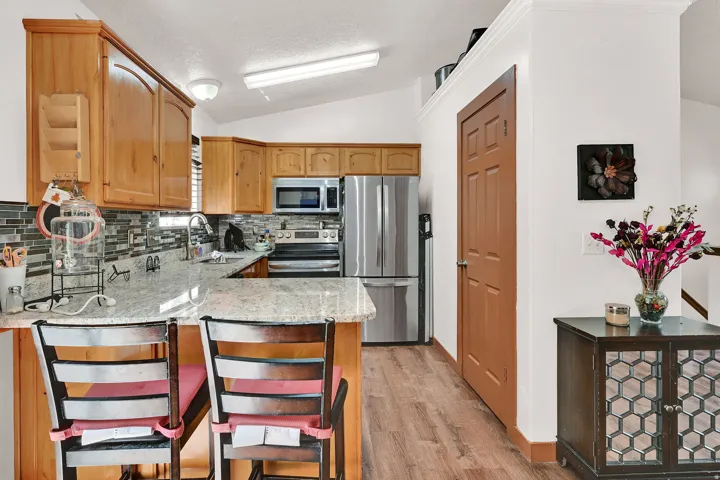 Kitchen featuring light stone countertops, stainless steel appliances, a peninsula, tasteful backsplash, and a kitchen breakfast bar