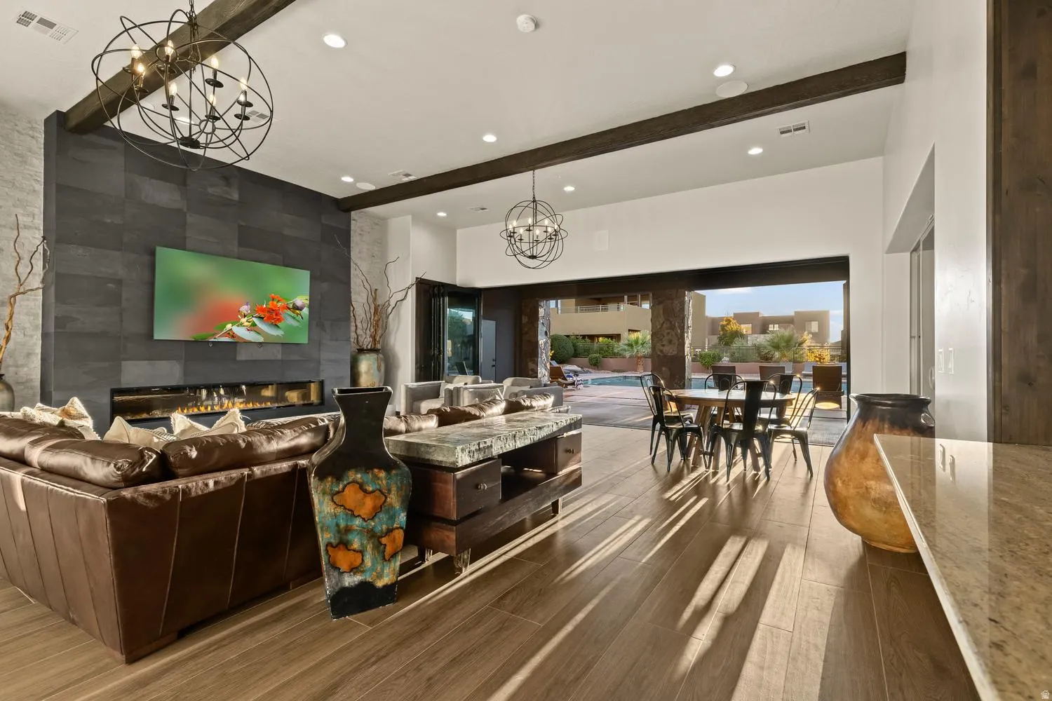 Living room featuring an accent wall, a tiled fireplace, hanging lights, and dark wood finished floors
