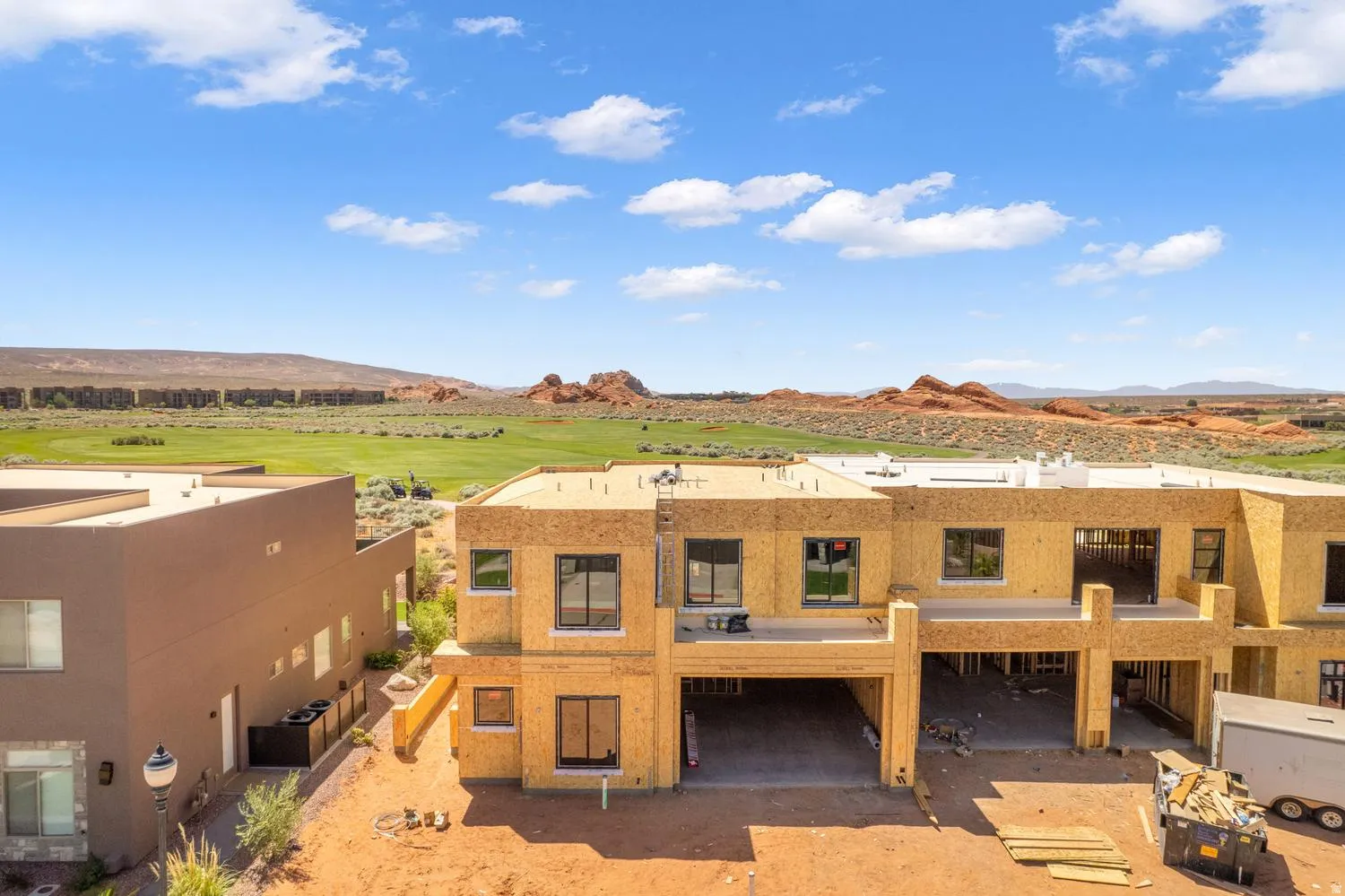 View of front of home with a mountain view, view of golf course, a patio area, and stucco siding