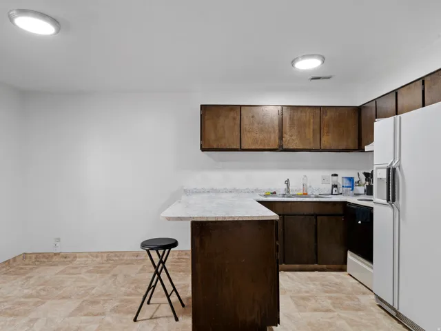 Kitchen featuring a peninsula, a kitchen breakfast bar, light countertops, and dark wood finish cabinets