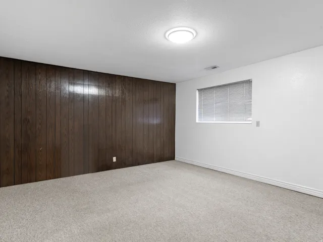 Carpeted spare room with wooden walls and a textured ceiling