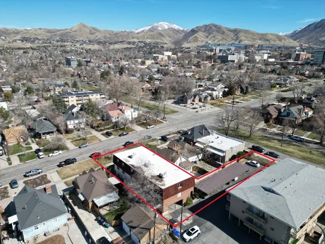 Aerial view of residential area featuring property boundaries highlighted and a mountainous background
