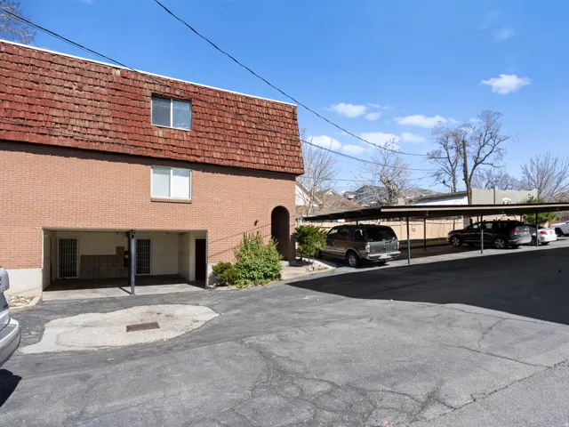 View of side of property with covered parking, mansard roof, and brick siding