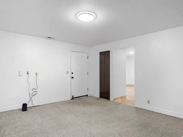 Empty room with light colored carpet and a textured ceiling