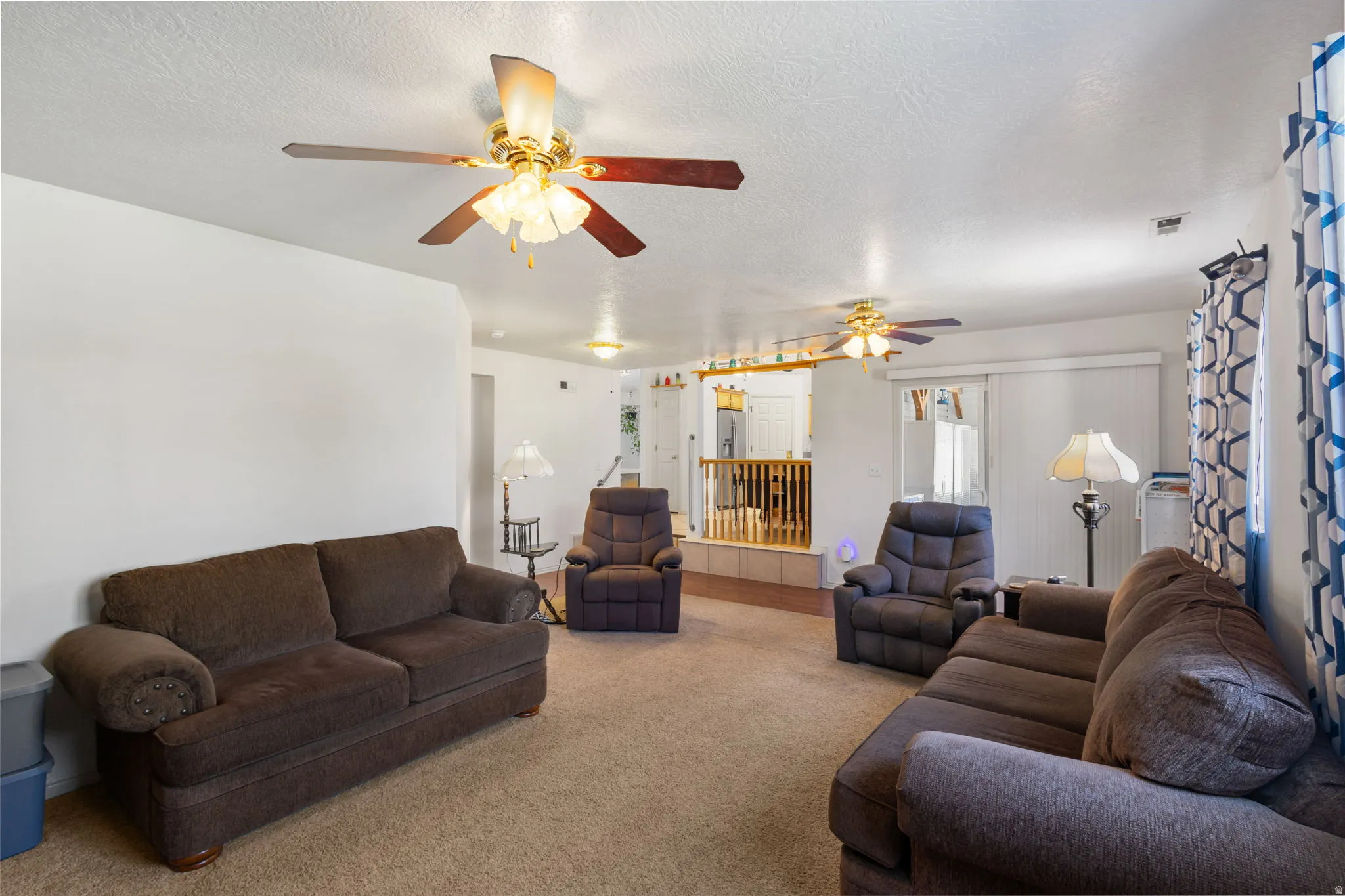 Living area featuring carpet, a textured ceiling, and ceiling fan