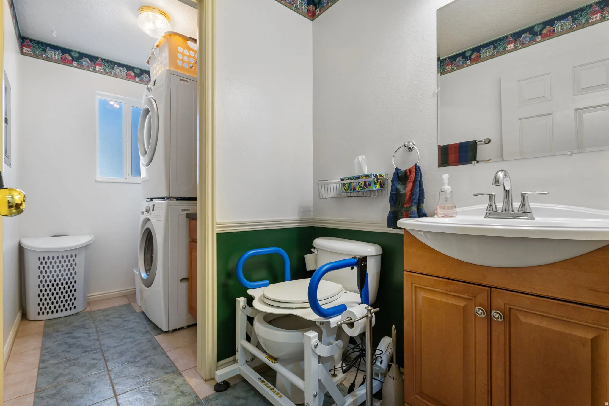 Bathroom with stacked washer and clothes dryer, vanity, and light tile patterned flooring