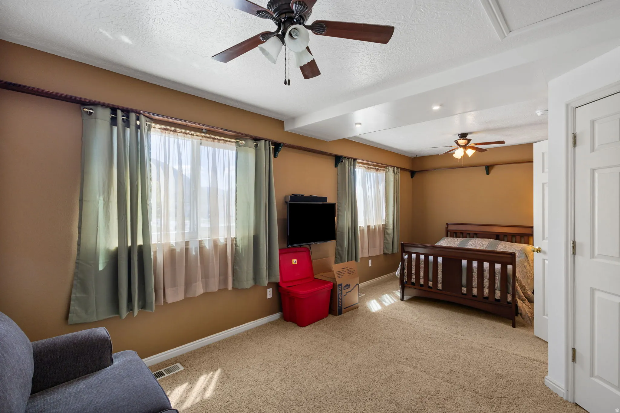 Bedroom with a textured ceiling, carpet flooring, and ceiling fan