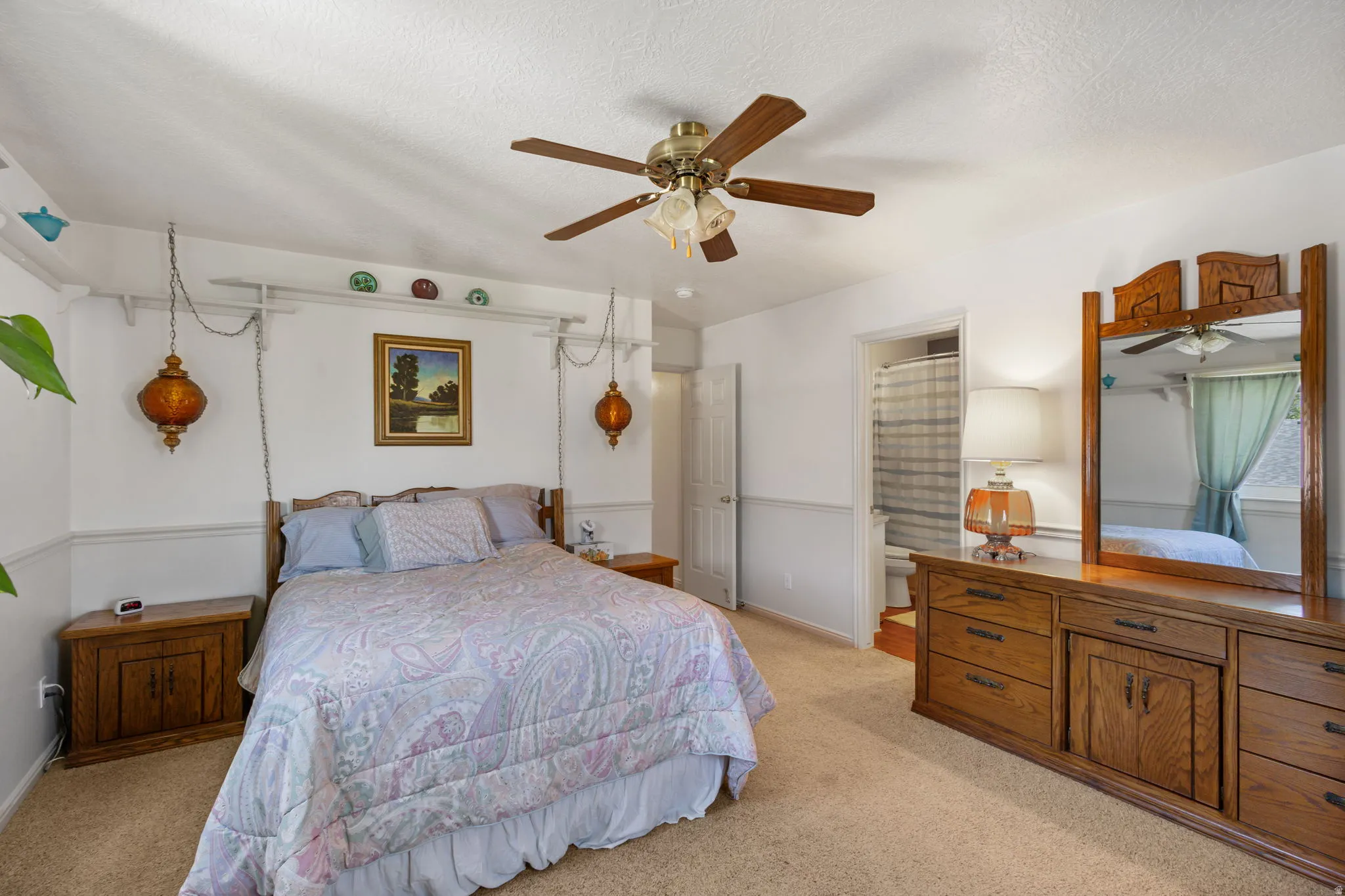 Bedroom featuring light colored carpet, ceiling fan, connected bathroom, and a textured ceiling