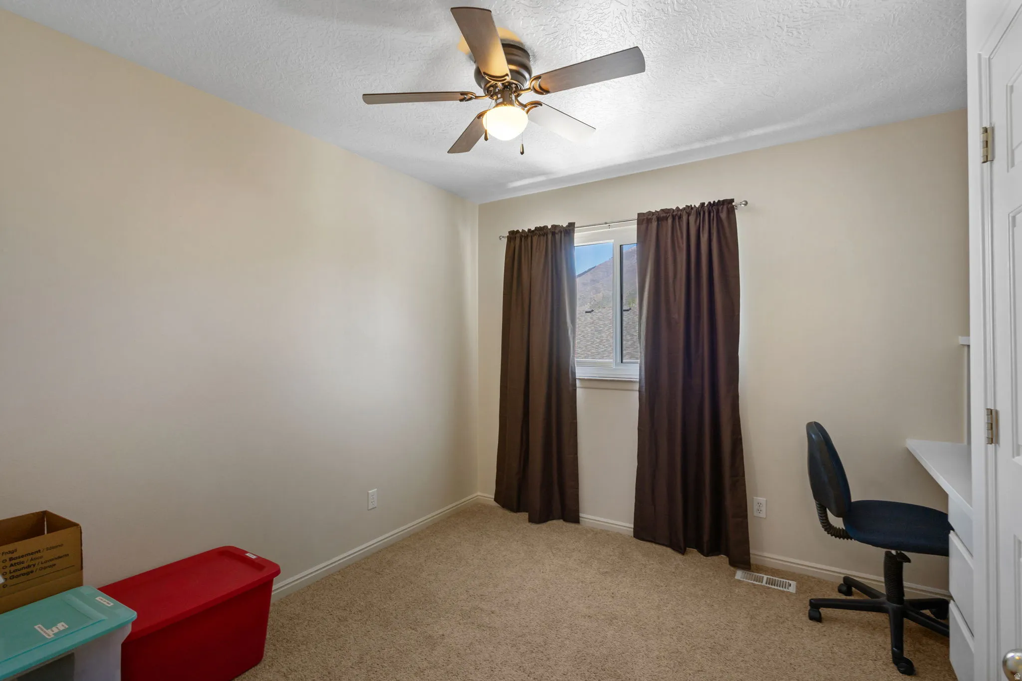 Office space with light colored carpet, a textured ceiling, and a ceiling fan